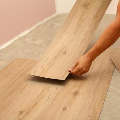 um profissional instala pranchas de piso laminado com padrão de madeira
