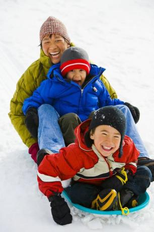 mãe e dois filhos 4 6 descendo a colina de trenó, rindo, vista elevada