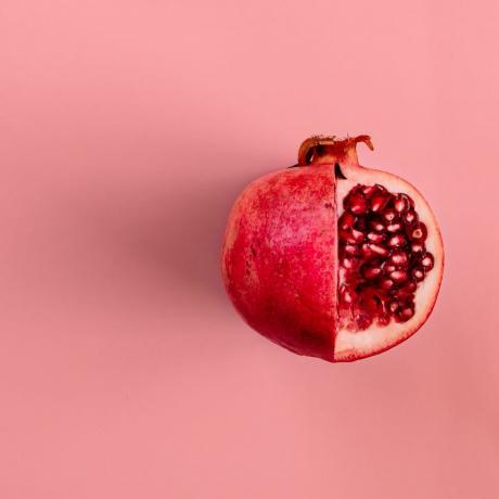 fruta de romã vermelha em fundo rosa pastel