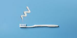 vista aproximada de uma escova de dentes branca plana e pasta de dente sobre fundo azul
